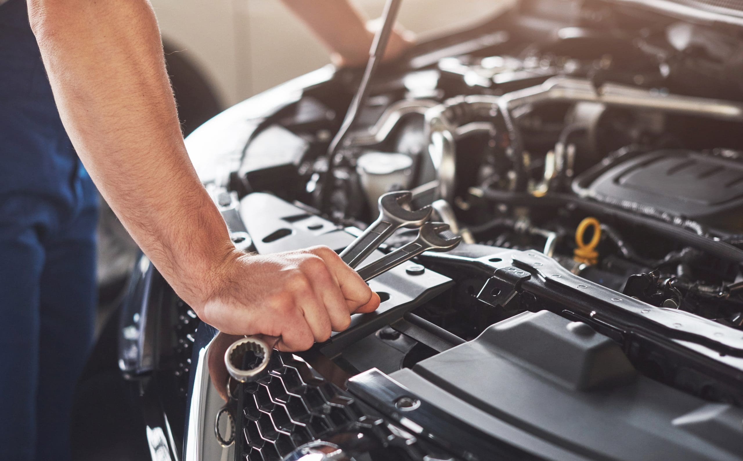 muscular car service worker repairing vehicle scaled